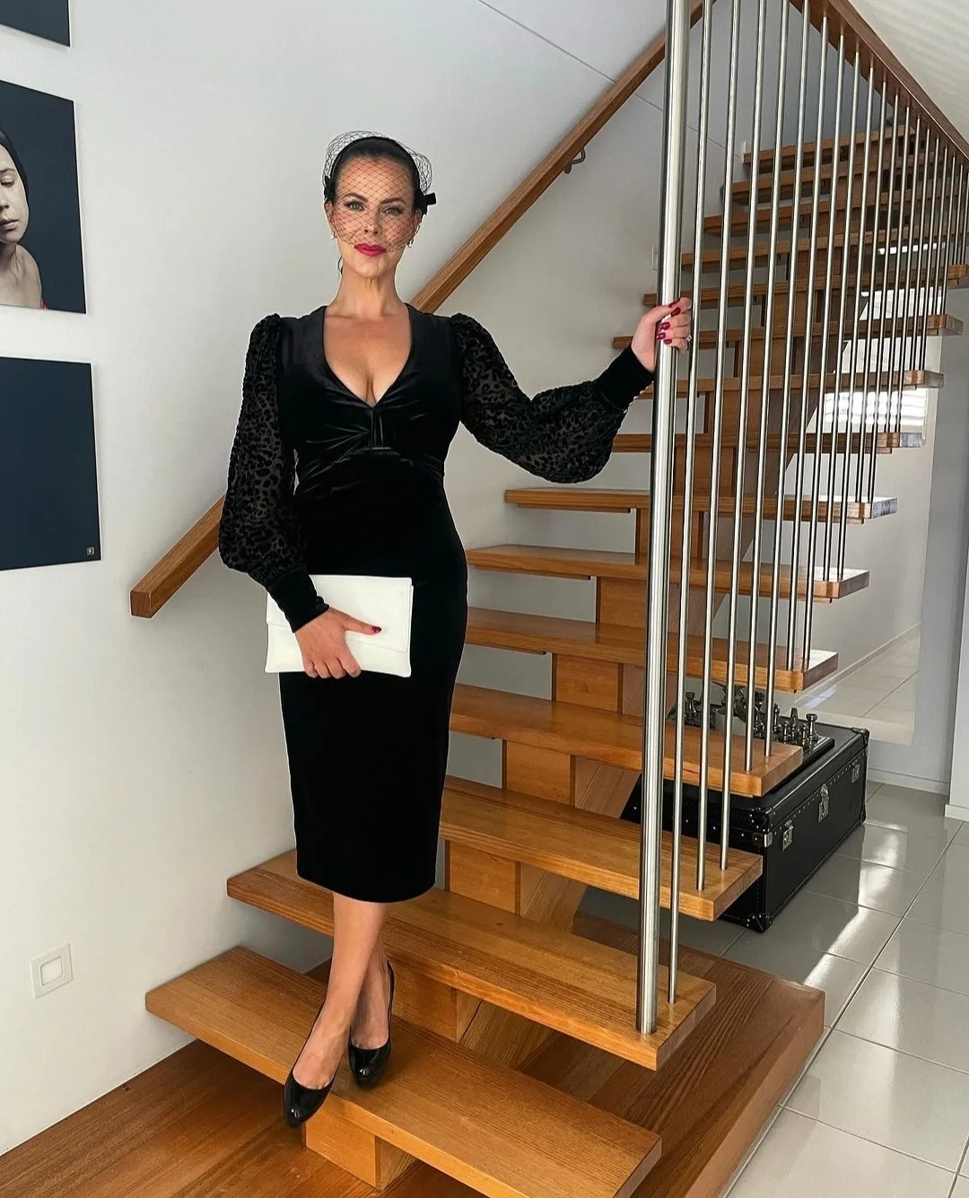 Client in black velvet on a timber staircase, glowing décolletage